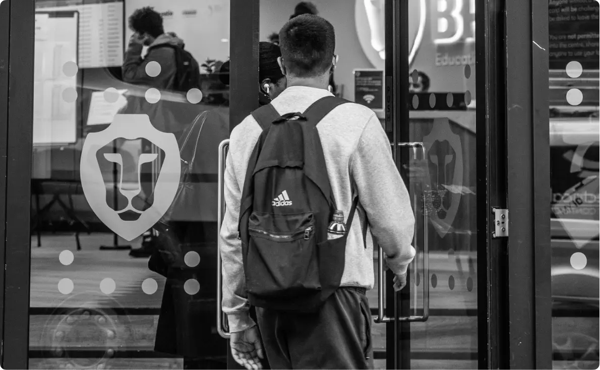 A student with a backpack walking through the glass doors of a BPP study centre